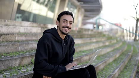 Man-using-laptop-and-smiling-at-camera